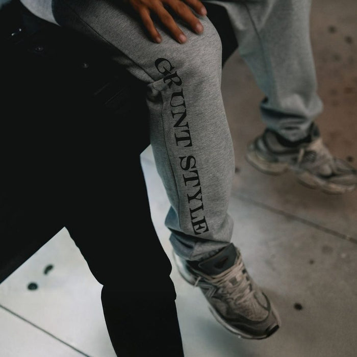 Person wearing gray 'Grunt Style' sweatpants with a blurred background