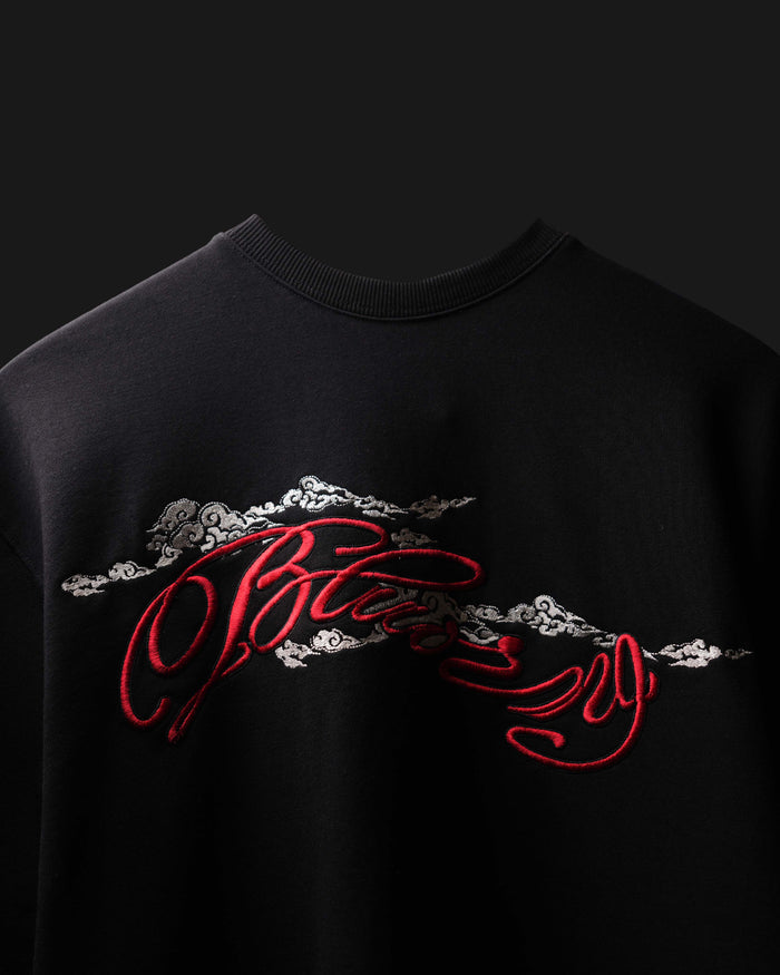 A close-up of a black crewneck sweatshirt featuring a large red and silver graphic print across the chest.