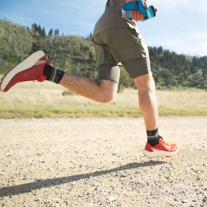 Person running on a trail with greenery in the background