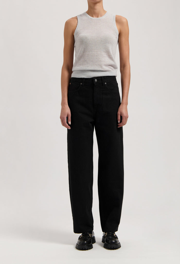 Model wearing a light gray sleeveless top and high-waisted black wide-leg jeans, paired with black shoes, against a plain background.