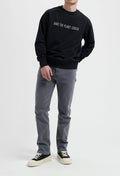 Sustainable MUD Jeans in light blue denim, crafted from organic cotton, styled with white sneakers and a gray t-shirt.