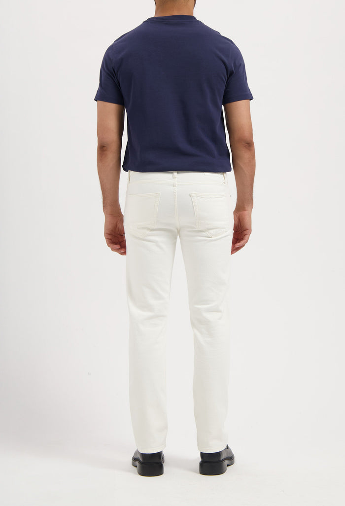 Sustainable MUD Jeans in dark indigo denim, paired with white sneakers, embodying ethical fashion.