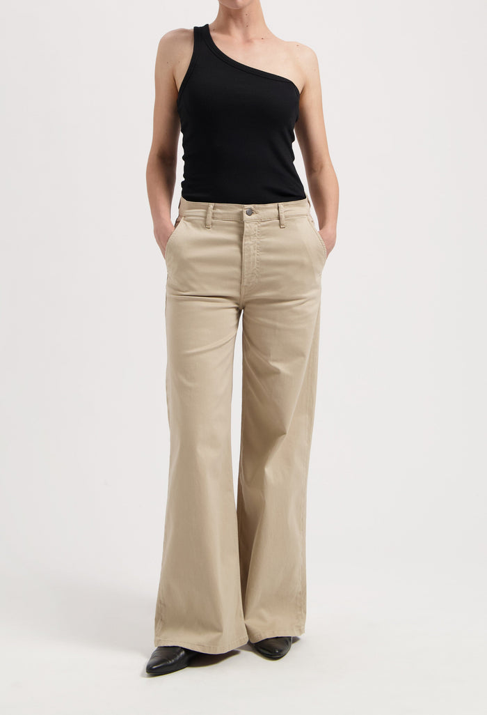 Wide-leg beige trousers paired with an asymmetrical black top, showcasing a minimalistic and stylish outfit.