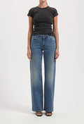 Wide-leg blue jeans with faded effect, paired with a fitted black short-sleeve top, worn by a model against a plain background.