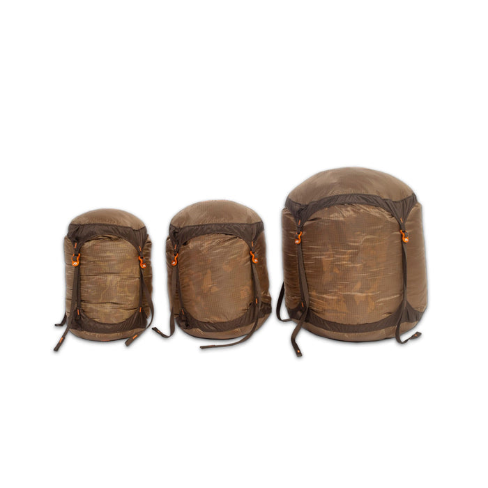Three varying-sized brown compression sacks with dark brown straps and orange buckles.