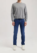 Sustainable MUD Jeans in deep blue denim, crafted ethically with organic cotton, paired with a casual gray t-shirt.