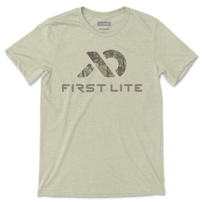 Heathered sage green t-shirt with a distressed camouflage logo above "FIRST LITE" text, and "MeatEater Medium" neck tags.