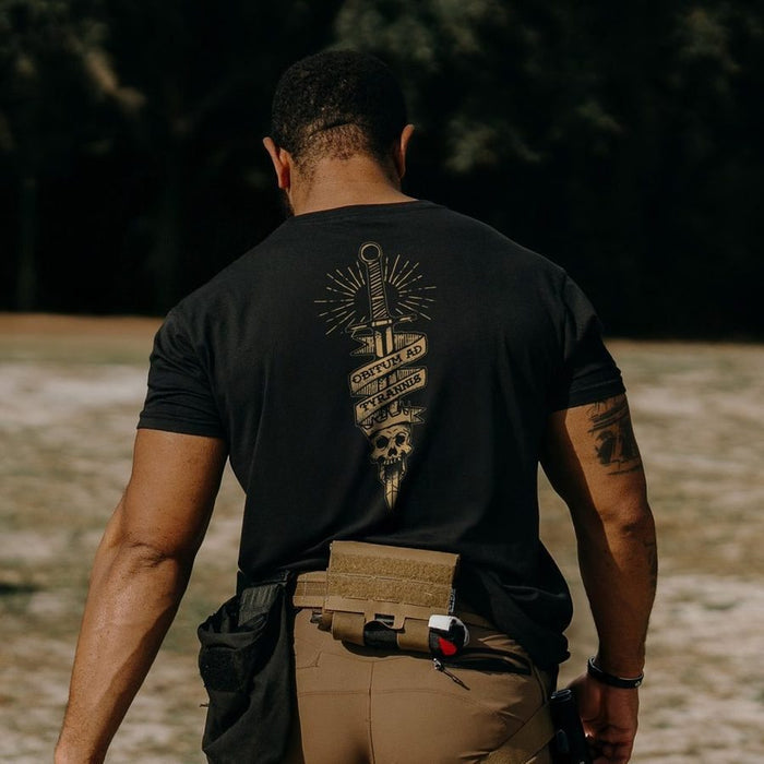 Man wearing a black t-shirt with a design on the back, standing outdoors.