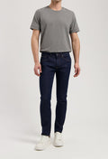 Sustainable MUD Jeans in a dark wash, crafted from organic materials, paired with a stylish gray sweater.