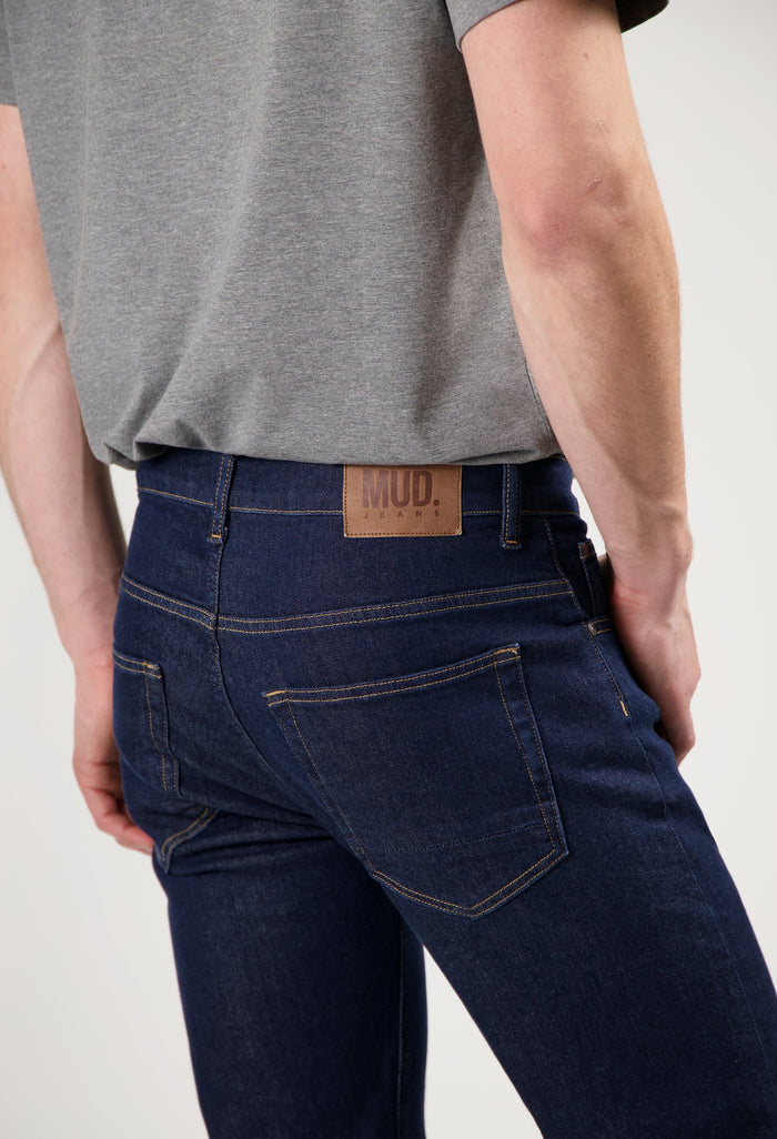 Mud Jeans sustainable light blue denim, crafted ethically from organic cotton, paired with a simple white long-sleeve shirt.