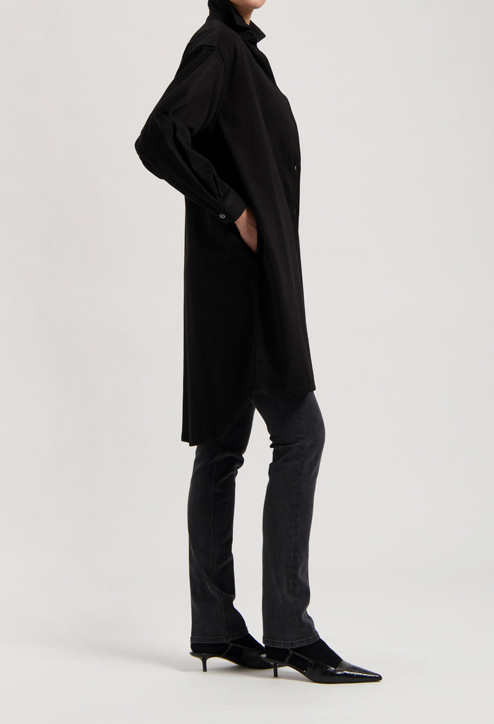 Black oversized shirt dress paired with dark gray, straight-leg jeans and pointed black kitten heels.