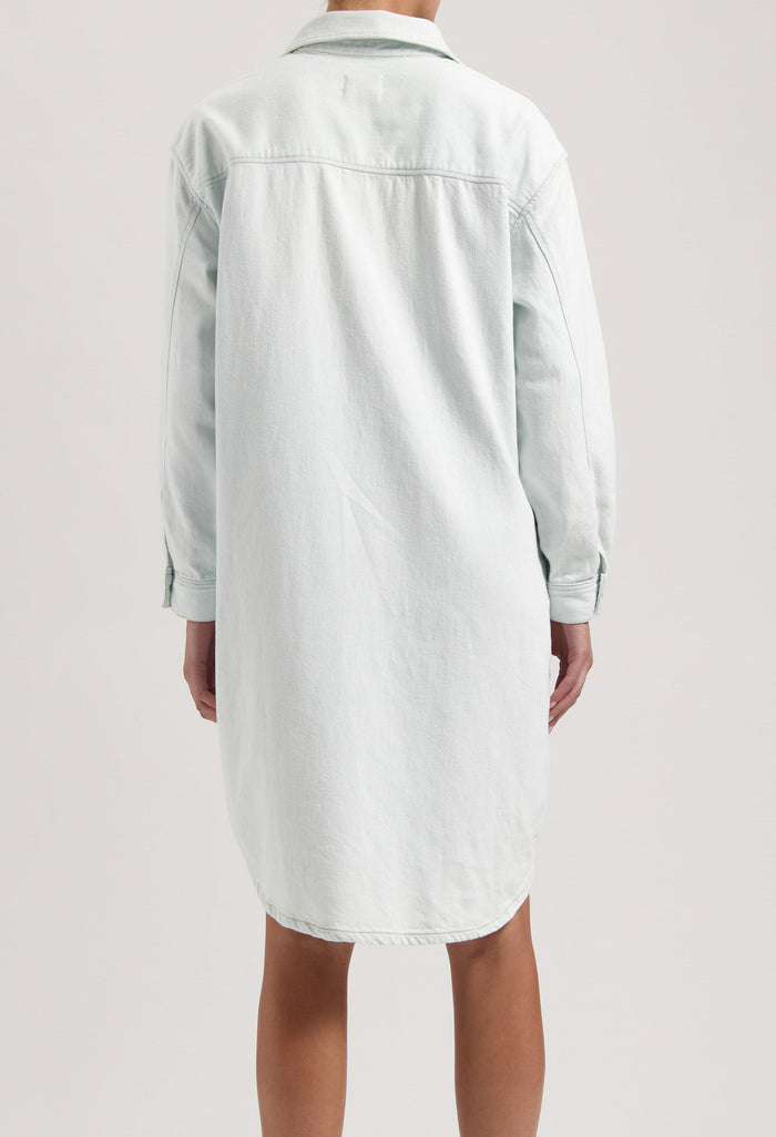 Back view of a light blue denim shirt dress showing a relaxed fit with long sleeves and classic collar design.