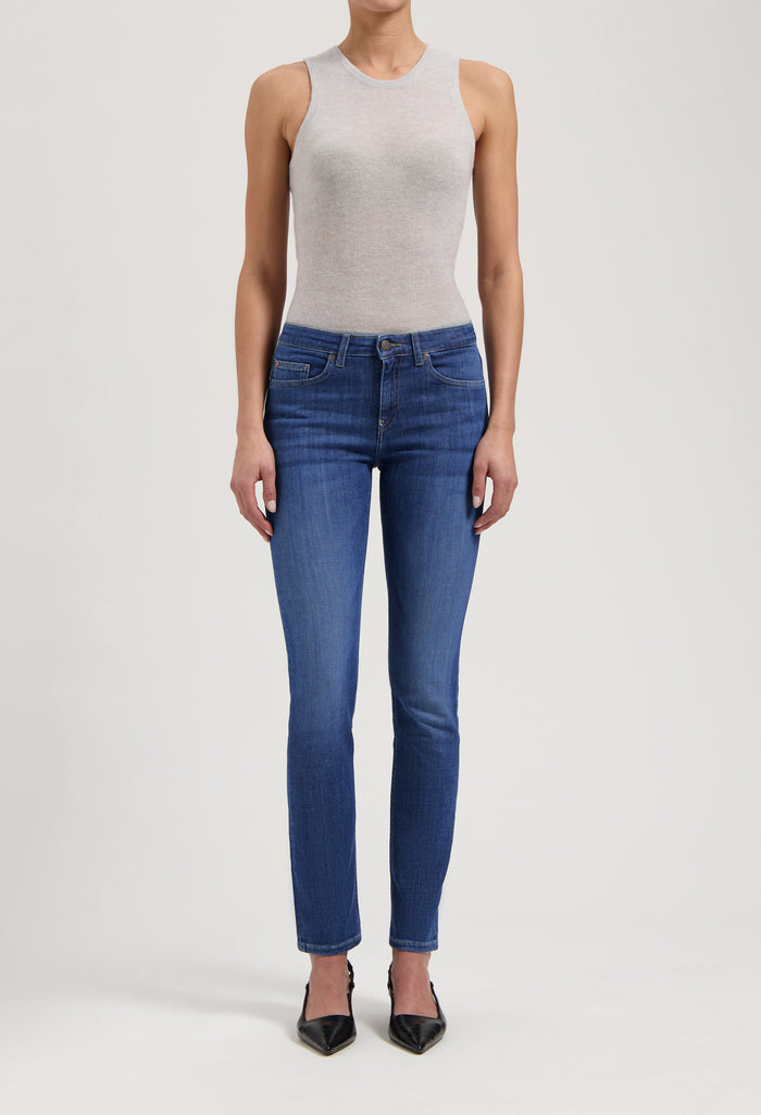 Slim-fit blue women’s jeans paired with a gray sleeveless top and black pointed-toe heels.