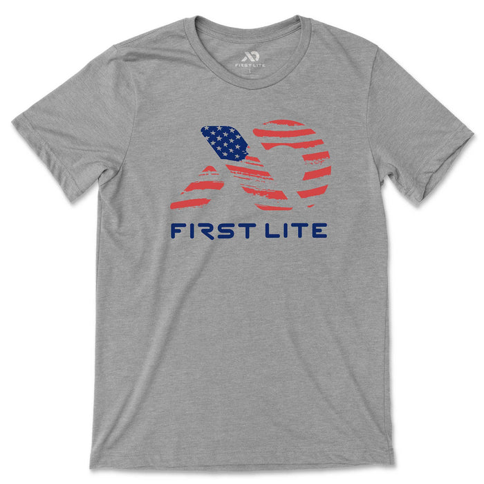 Grey t-shirt with a First Lite logo on the chest, stylized with an American flag pattern and "FIRST LITE" text below it.