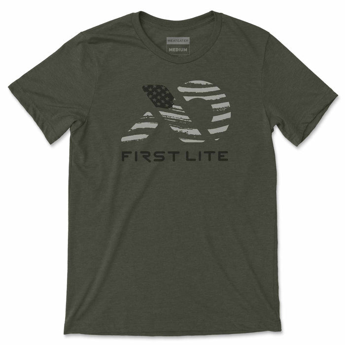 Dark olive green t-shirt featuring a distressed light gray mountain logo with an American flag design and "FIRST LITE" text below.