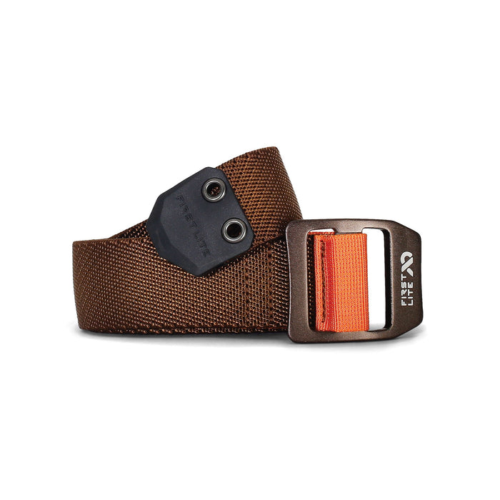 A brown woven belt with a black end piece and two grommets, featuring a bronze buckle with orange webbing and First Lite branding.