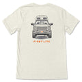 Heather cream t-shirt with a graphic of a front-facing pickup truck, a camper top, off-road tires, a rifle visible through the windshield, and orange "FIRST LITE" text.