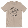 Beige t-shirt with 'First Lite Idaho' baked potato graphic on a white background