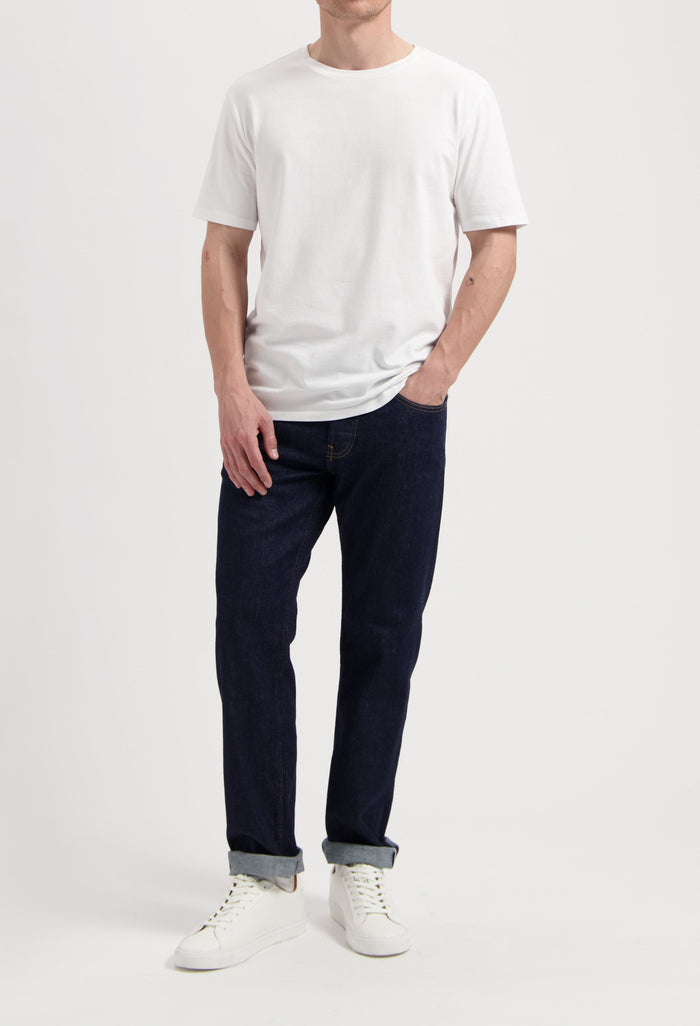 Sustainable MUD Jeans ensemble with dark denim jacket, light blue jeans, and white sneakers, embodying ethical fashion.