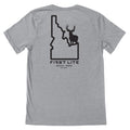 Light gray t-shirt with a black graphic on the back showing an Idaho state outline with a deer silhouette inside and text "FIRST LITE HAILEY, IDAHO EST.2007"