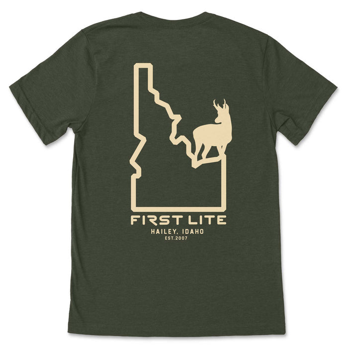 Dark green t-shirt with a beige graphic on the back featuring the outline of Idaho state containing a pronghorn antelope silhouette, and "FIRST LITE HAILEY, IDAHO EST.2007" text below.