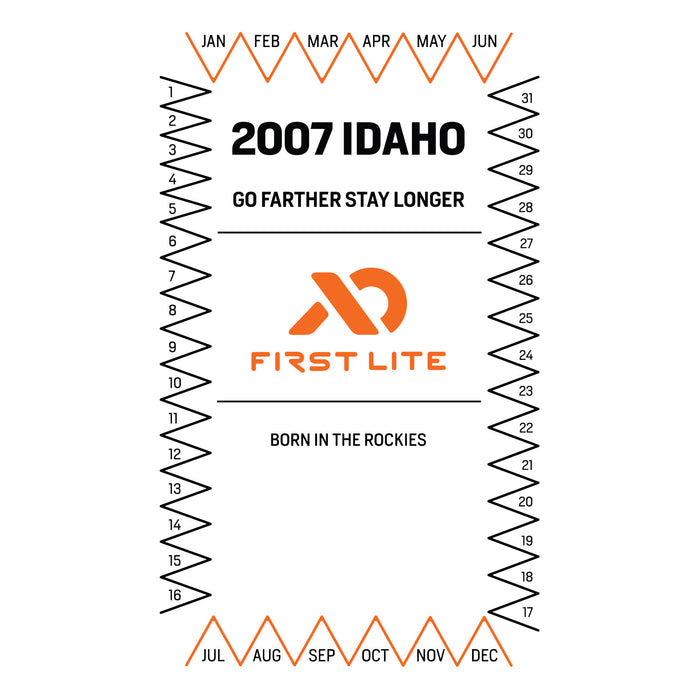 White graphic with an orange and black calendar-style border listing months and days, surrounding the orange First Lite logo and black text '2007 IDAHO', 'GO FARTHER STAY LONGER', and 'BORN IN THE ROCKIES'.