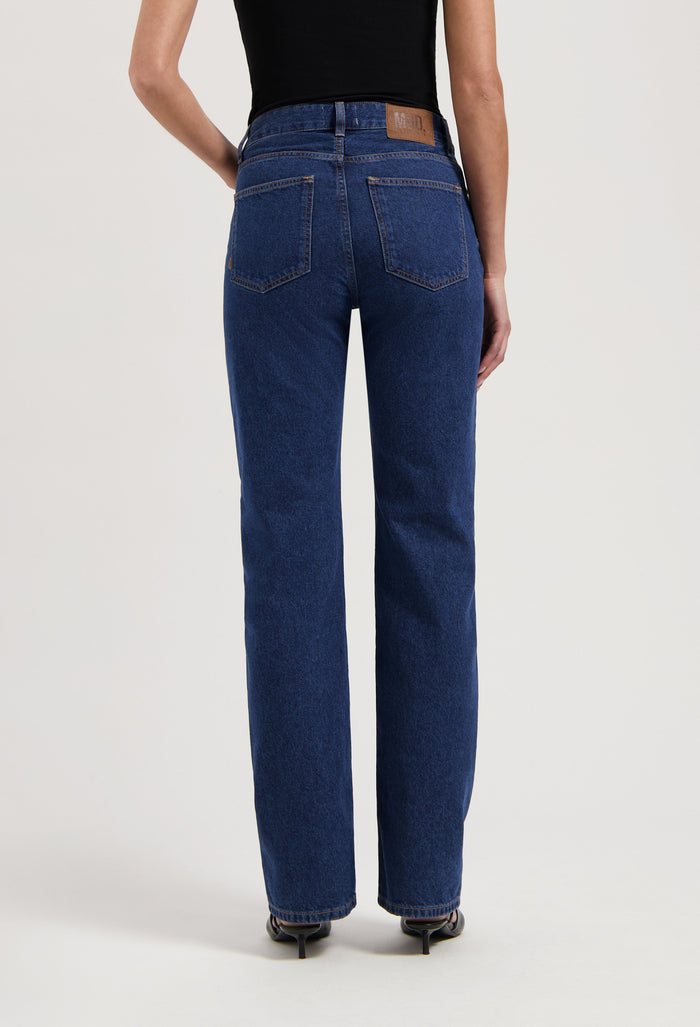 High-waisted, eco-friendly deep blue women's jeans showcasing straight-leg fit, paired with a black sleeveless top.