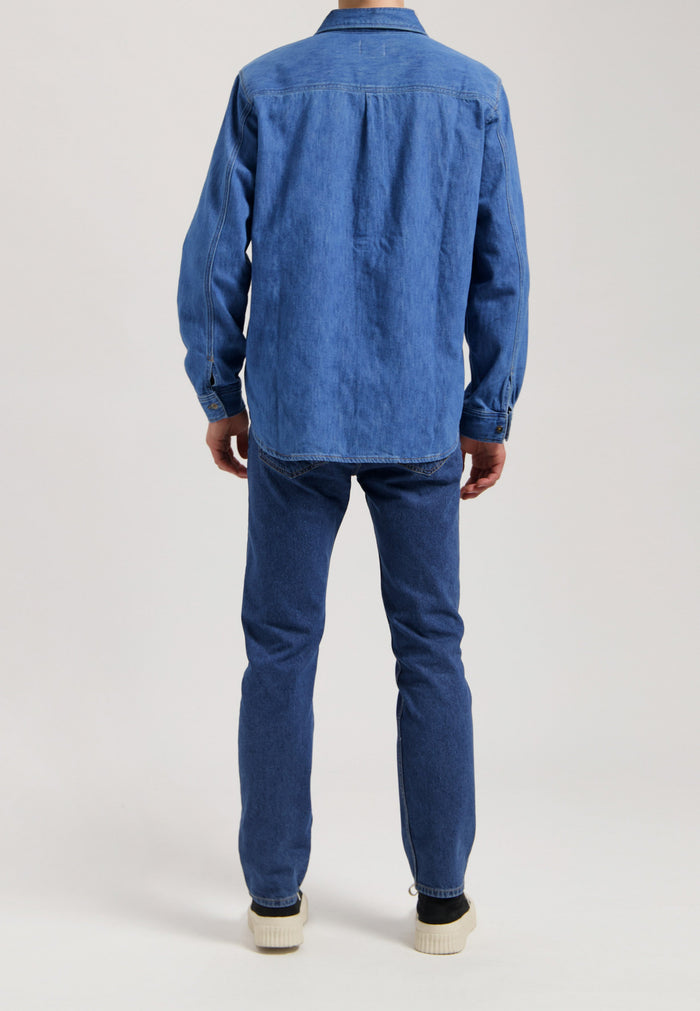 Sustainable MUD Jeans in dark denim, featuring a straight fit with ethical craftsmanship, paired with a white top.
