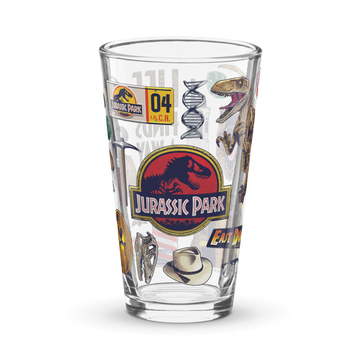 Clear 16 oz pint glass featuring vibrant Jurassic Park icons and dinosaur graphics printed in color on the front
