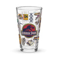 Clear 16 oz pint glass featuring vibrant Jurassic Park icons and dinosaur graphics printed in color on the front