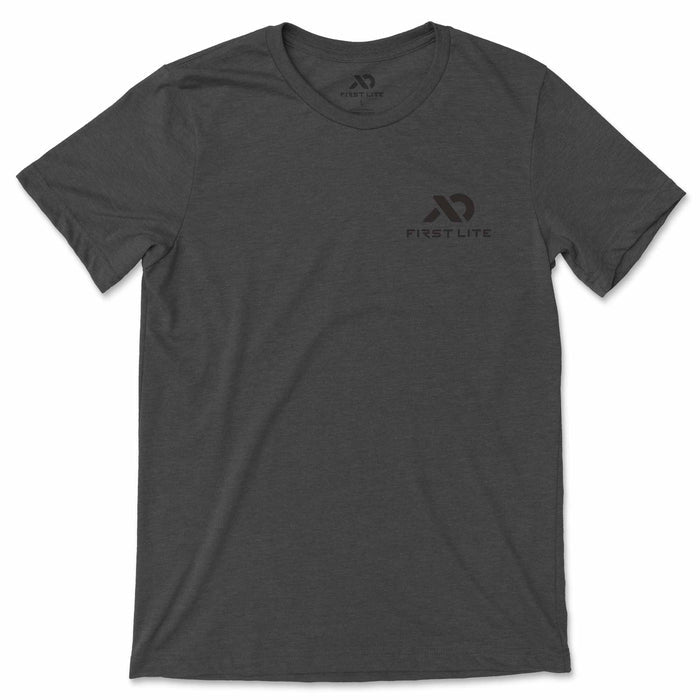 Dark grey heathered t-shirt with a round neck, short sleeves, and a subtle dark grey First Lite logo on the left chest, with a size L label visible inside the neck.