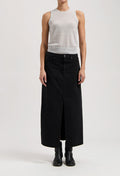 Model wearing a sleeveless gray top with a long black denim skirt, featuring a central slit, and black ankle boots.