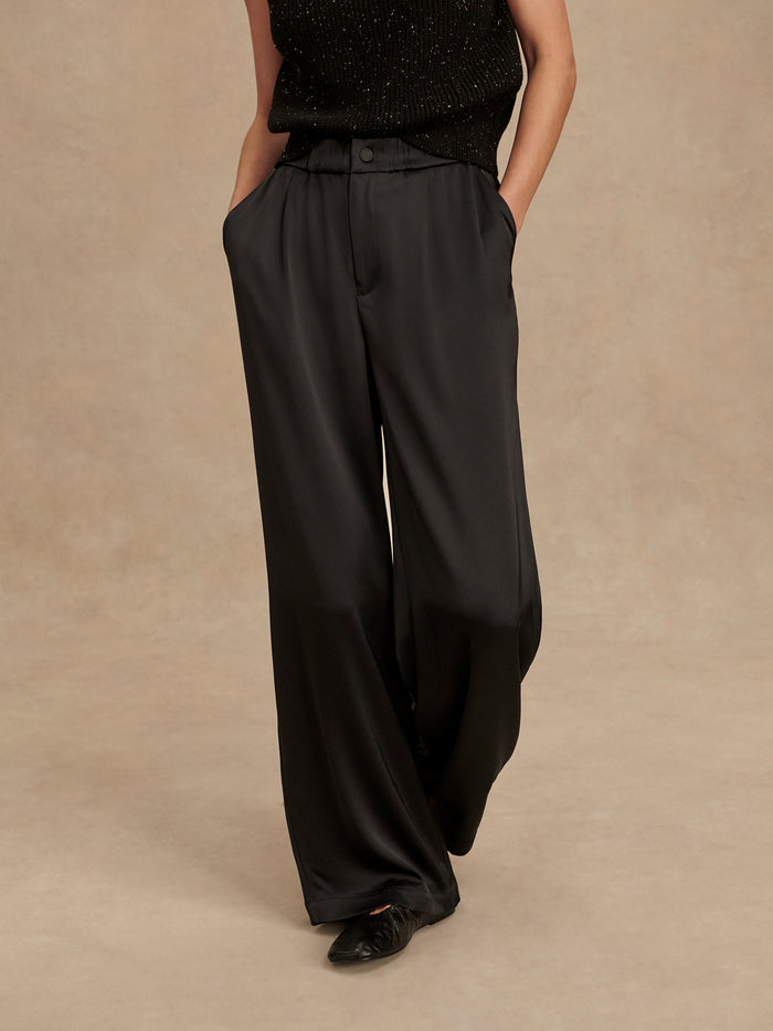 Black|Bryden 2.0 Wide Leg Pant 32 in black, semi-gloss Sateen fabric with front pleats, side pockets, snap front and fly, and elasticated waistband.
