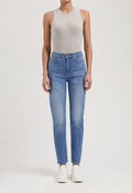 Woman wearing light gray sleeveless top and high-waisted blue jeans, paired with white sneakers, isolated on white background.