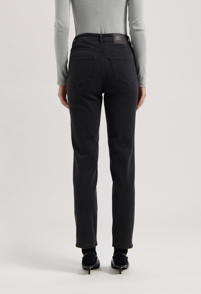 Back view of black, high-waisted denim jeans worn with a fitted gray long-sleeve top, showcasing modern casual fashion.