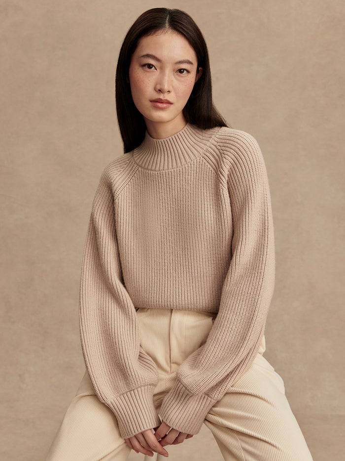 Cement|Varley Martina High Neck Rib Knit Cement, front view of a model wearing a rib-knit sweater with a high neckline in cement color and long sleeves.