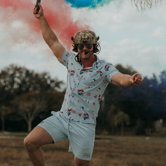 Man in a patterned shirt and shorts with colorful smoke effects in the background