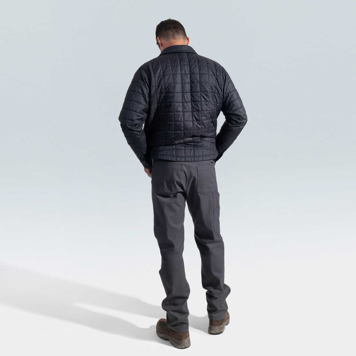 Man wearing a black quilted jacket and gray pants on a light gray background