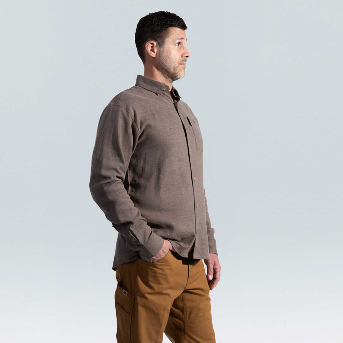 Man wearing a brown shirt and brown pants against a light gray background