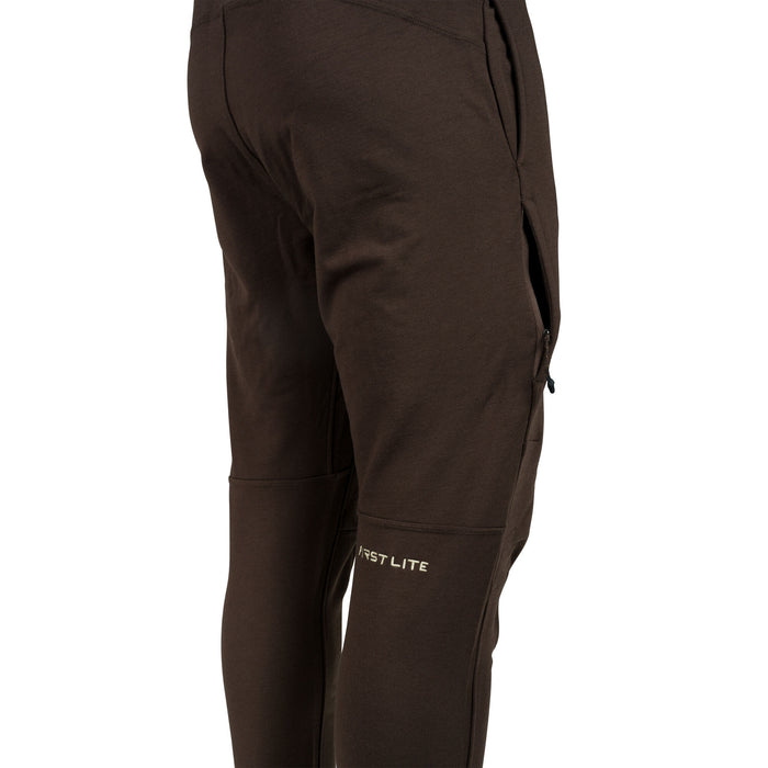 Dark brown pants featuring a zippered side pocket, articulated knees, and a "FIRST LITE" logo on the lower leg.