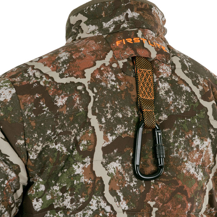 Close-up of the back of a brown, green, and white camouflage jacket, featuring an orange FIRST LITE logo, and a black carabiner on an orange strap.