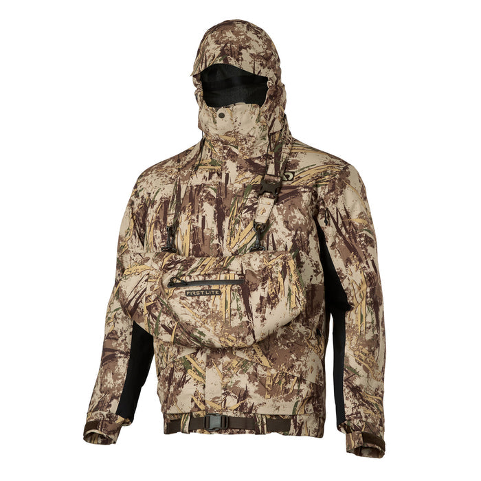 A First Lite camouflage hunting jacket featuring an integrated hood with black mesh face mask, a large chest pouch, black side panels, and a waist belt.