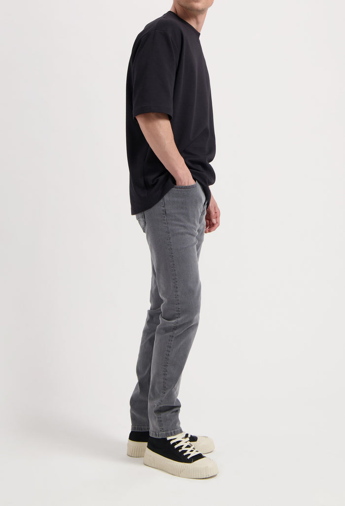 Sustainable MUD Jeans in light blue denim, crafted ethically, paired with a white long-sleeve shirt.