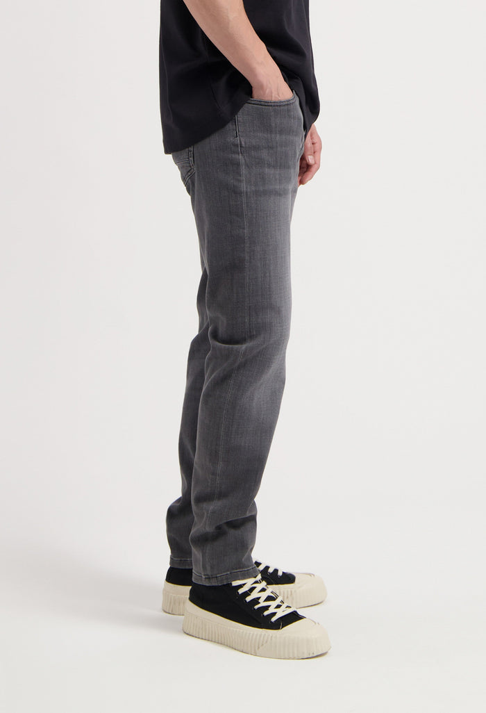 Sustainable MUD Jeans in light blue denim, crafted ethically, featuring a classic fit, paired with a white top.