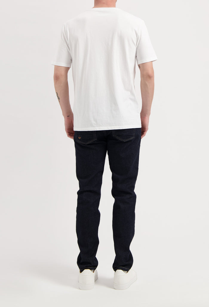 Sustainable MUD Jeans in classic blue denim, crafted from organic cotton, paired with white sneakers and gray sweater.