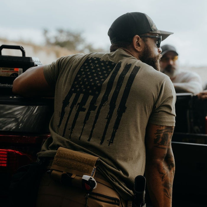 Man wearing a t-shirt with an American flag design, sitting outdoors.