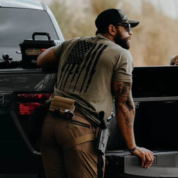 Man leaning against a black pickup truck with a tactical setup