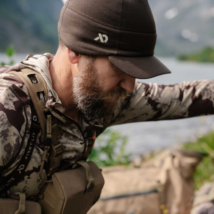 Dark brown fleece cap with a brim and white First Lite logo on the side.