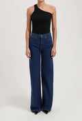 Wide-leg high-waisted jeans in deep blue, paired with a black one-shoulder top, showing a casual yet stylish look.