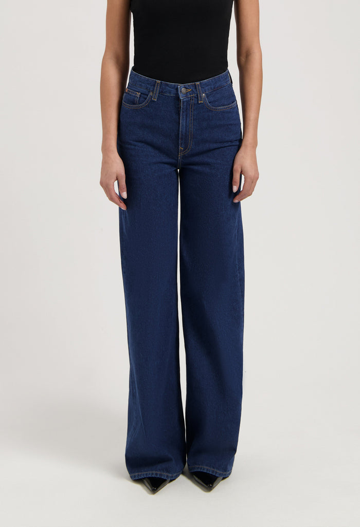 Wide-leg blue denim jeans paired with a black sleeveless top, showing high-waisted style and casual elegance.